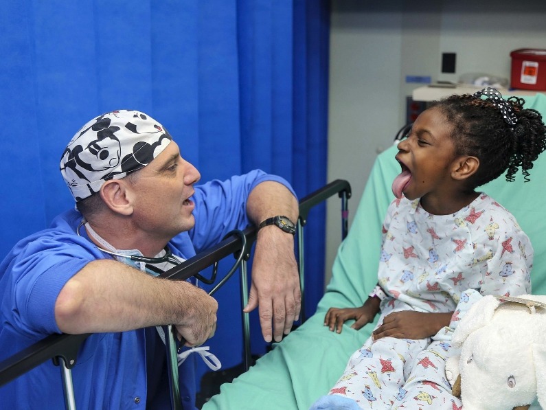 doctor or surgeon leaning over a little girl's bedside in the hospital