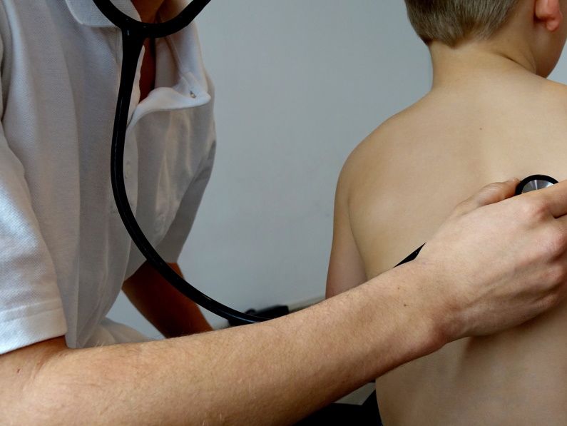 doctor holding a stethoscope up to a child's back