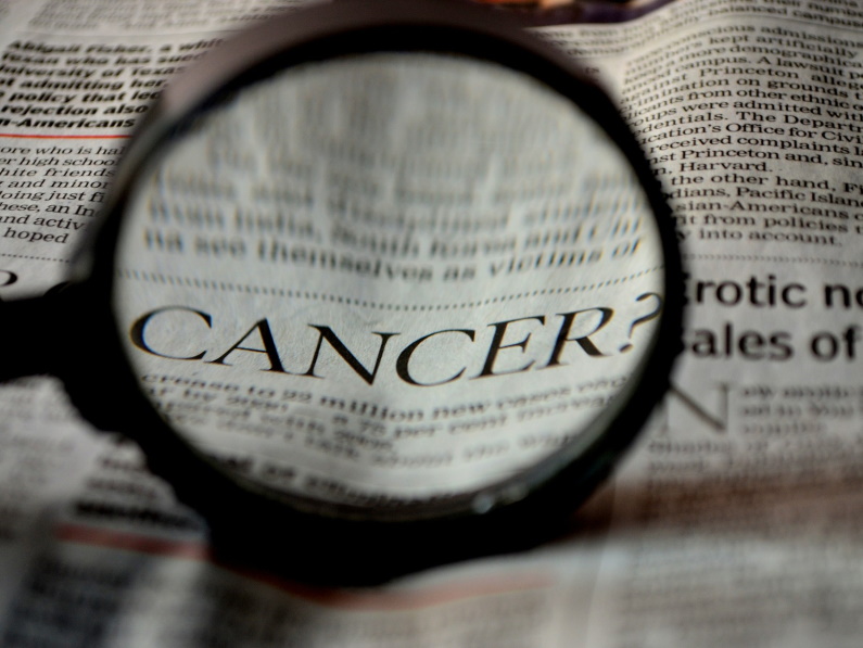 magnifying class over newspaper headline titled cancer